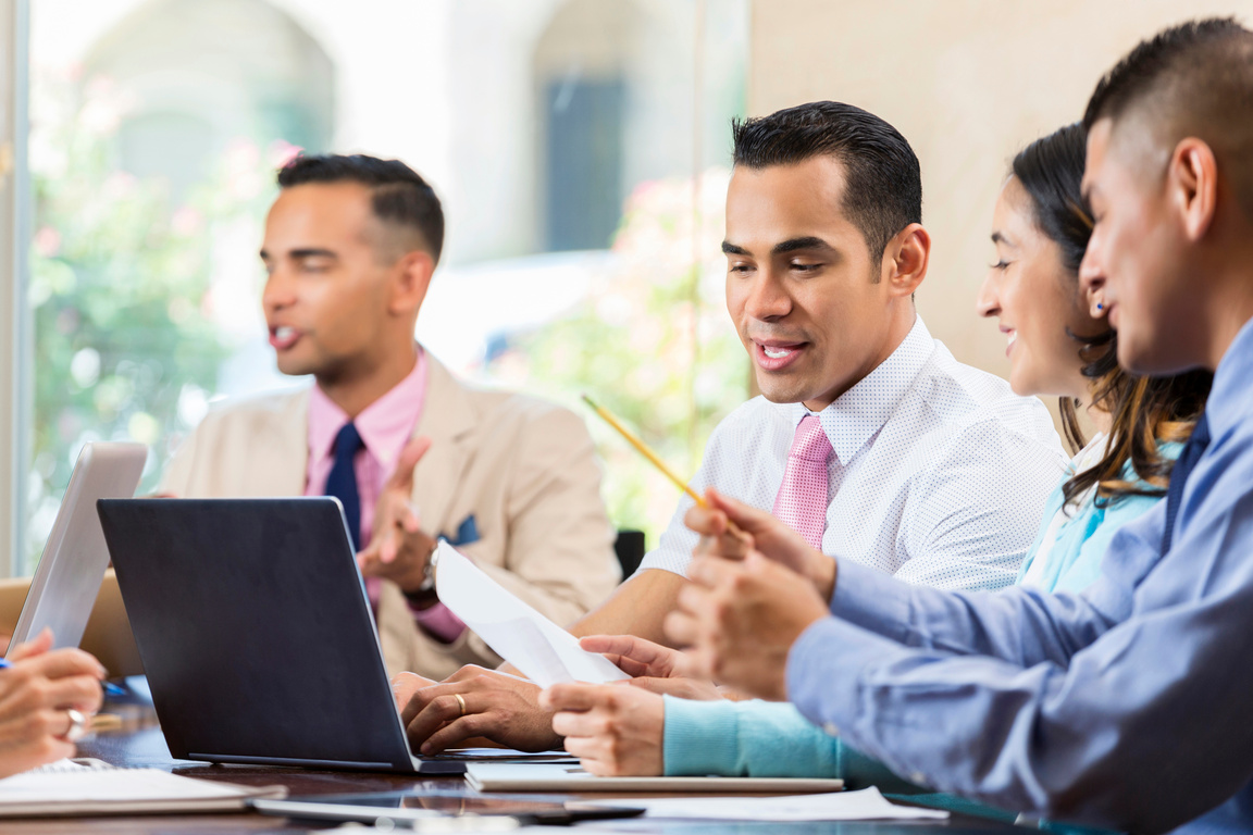 Hispanic business professionals talks during staff meeting